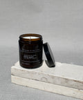 Sharp peels soy candle by house of two trees, amber glass jar with a black lid and a cream label