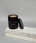 Morning forest soy candle by house of two trees, amber glass jar with a black lid and a cream label